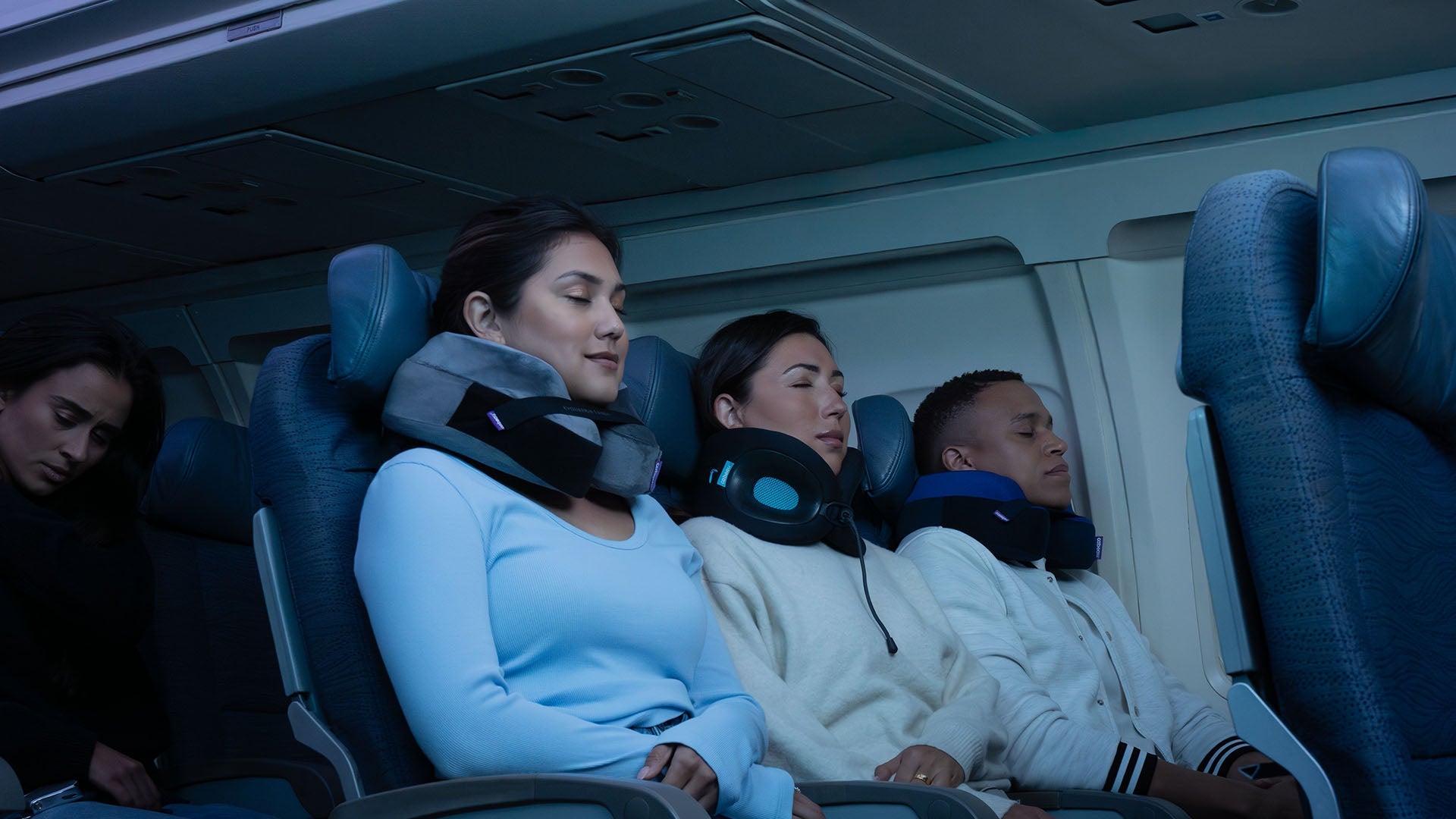 Three travelers sleeping on an airplane comfortably wearing neck pillows