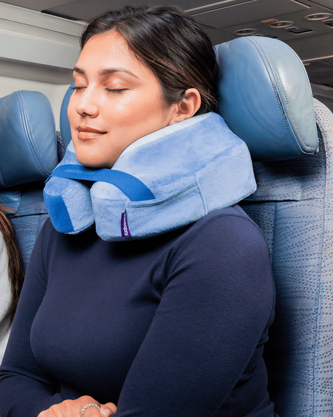 Woman using a travel neck pillow on an airplane seat