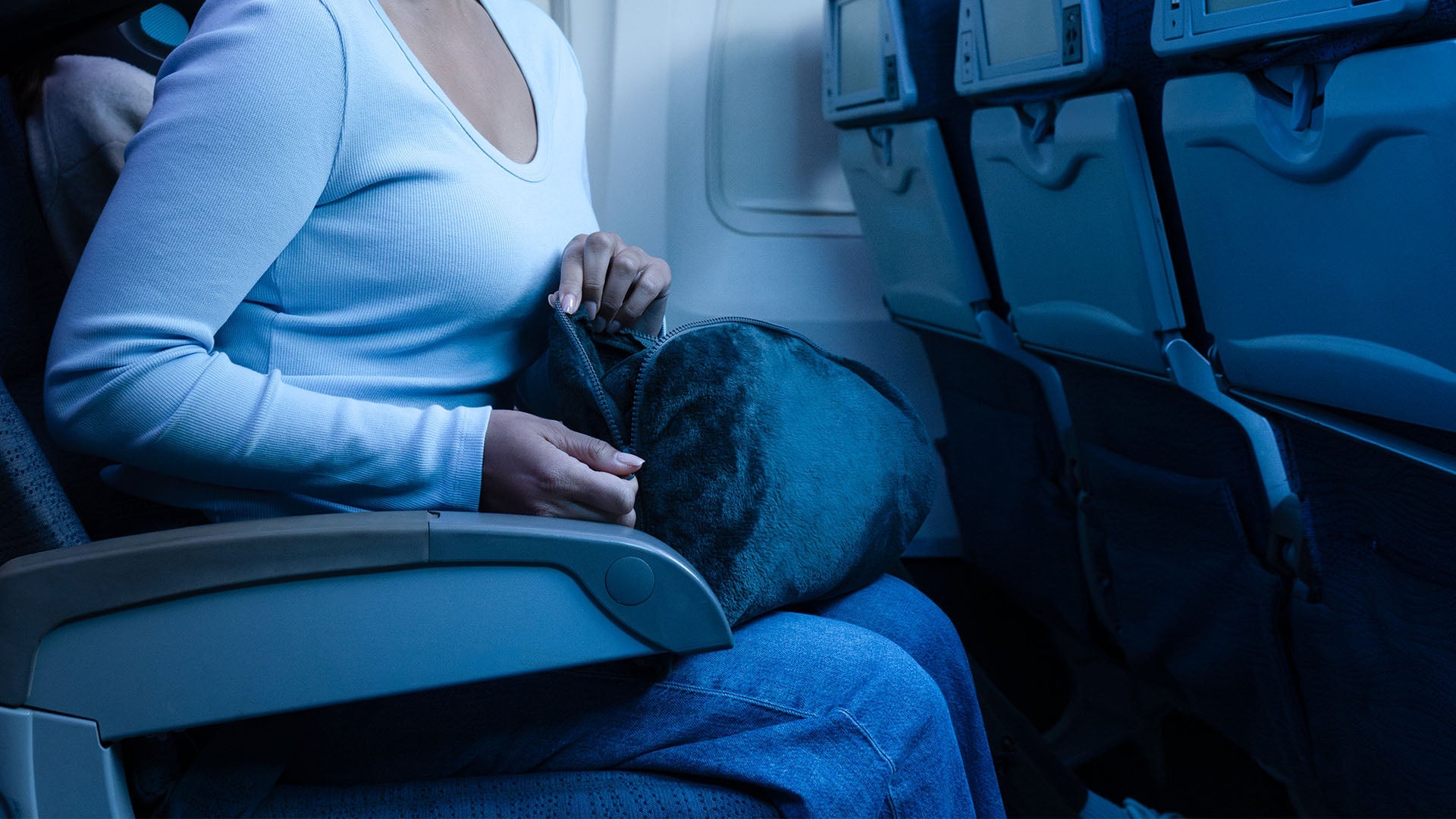 Woman unzipping our Fold 'n Go travel blanket. The blanket comes with its own travel case and is luxuriously soft.