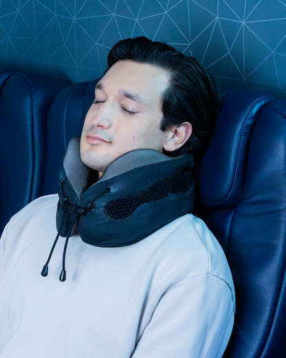 Man using a neck pillow in a plane seat, sleeping comfortably with Evolution Cool pillow