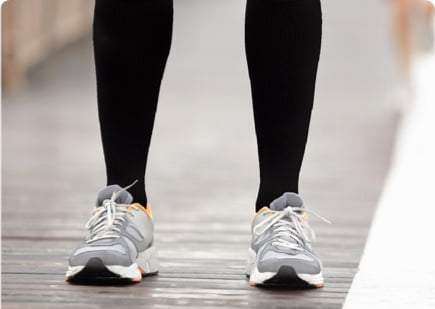 Photo of legs wearing the black bamboo compression socks and wearing grey athletic shoes 